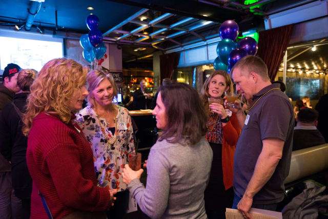 Group of attendees engaging in conversation at the Love Bomb 2017 event, with festive decorations and a lively atmosphere, supporting My Voice Music nonprofit.
